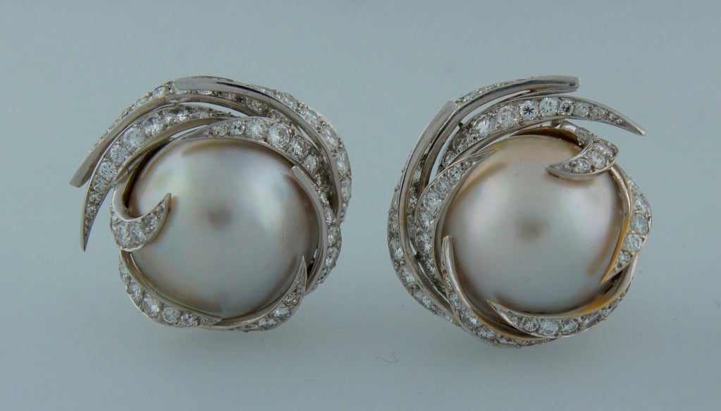 Stunning elegant earrings created by Pierre Sterle in Paris in the 1950's. Feature two mobe pearls framed in elegant diamond swirl. Mobe pearls are 18.39 mm in diameter. Diamonds are round cut, total weight approximately 3 carats.
Very feminine,