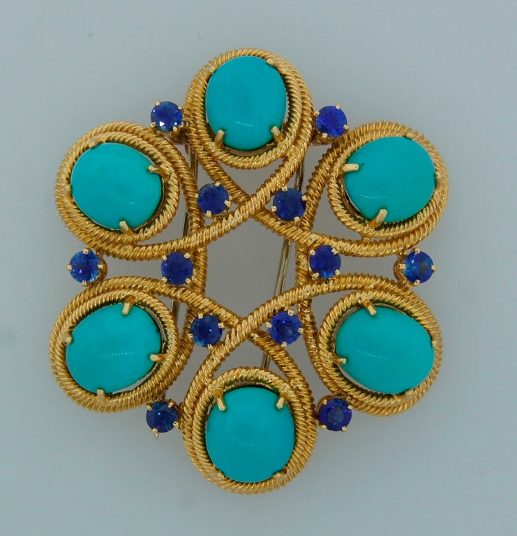 Prominent and colorful brooch created by Van Cleef & Arpels in France in the 1950's. Features six oval turquoise tastefully framed in yellow gold  and sprinkled with round sapphires. Sapphire total weight 1.65 carats. The brooch is 1.75 inches in