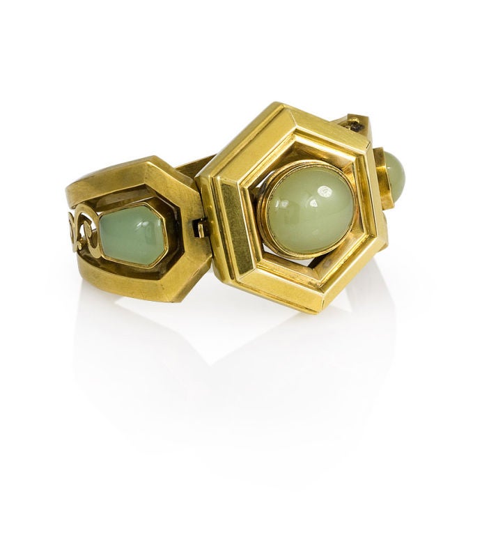 An antique green chalcedony bangle bracelet set with a central oval stone in a hexagonal panel, bordered on either side by shield-shaped stones, and openwork sections, in 14-15k.