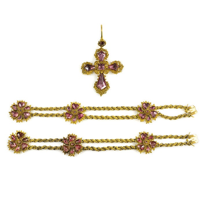 A suite of antique gold and foiled pink quartz jewelry comprised of a floral necklace, a brooch, a pair of bracelets and a cross pendant in a fitted rosewood case, in 18k.