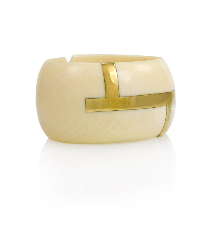 A carved ivory hinged cuff bracelet inlaid with a geometric gold motif, in 20k.