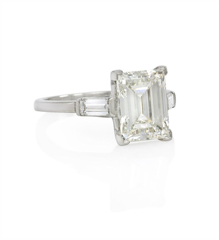 An Art Deco diamond engagement ring, with a rectangular step cut diamond flanked by two baguette cut diamonds, set in platinum. Approximate total weight of center stone: 2.94 carats. J, VS1. GIA cert on center stone. Approximate total weight of all