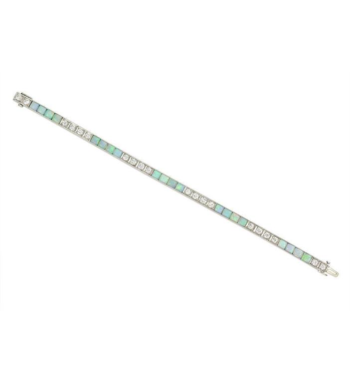 An Edwardian diamond and opal line bracelet designed as alternating groups of four round diamonds with four buff top opals, in platinum.