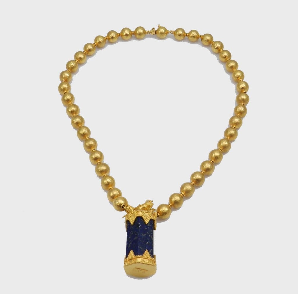 Handmade 22kt. yellow gold necklace reminiscent of Ancient Egyptian orinamentation. The necklace is compossed of 39 hand hammered beads with a column of lapis lazuli topped by a gold scarab beetle.