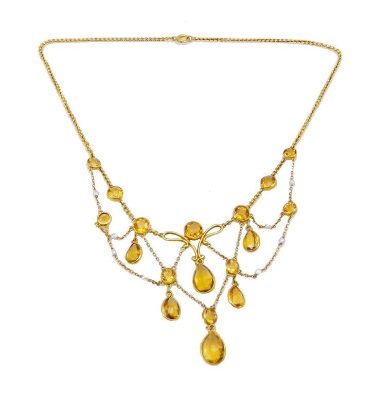 Graceful natural citrine and Belle Epoque seed pearl festoon style necklace in 14kt. yellow gold with 12 bezel set round faceted citrines and 6 pear shape citrines. There are 8 seed pearl accents. Circa. 1900. The necklace measures 15