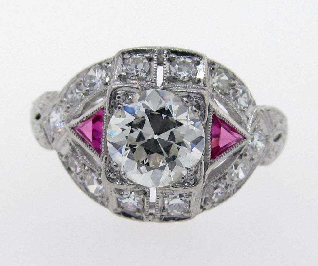 Lovely Art Deco Diamond and Ruby Ring. Prong set with a center round European cut diamond weighing approx. 1.08 cts. Bead set with an additional 14 round old cut diamonds totaling approx..45 cts. with 2 accent triangular cut rubies. The ring is