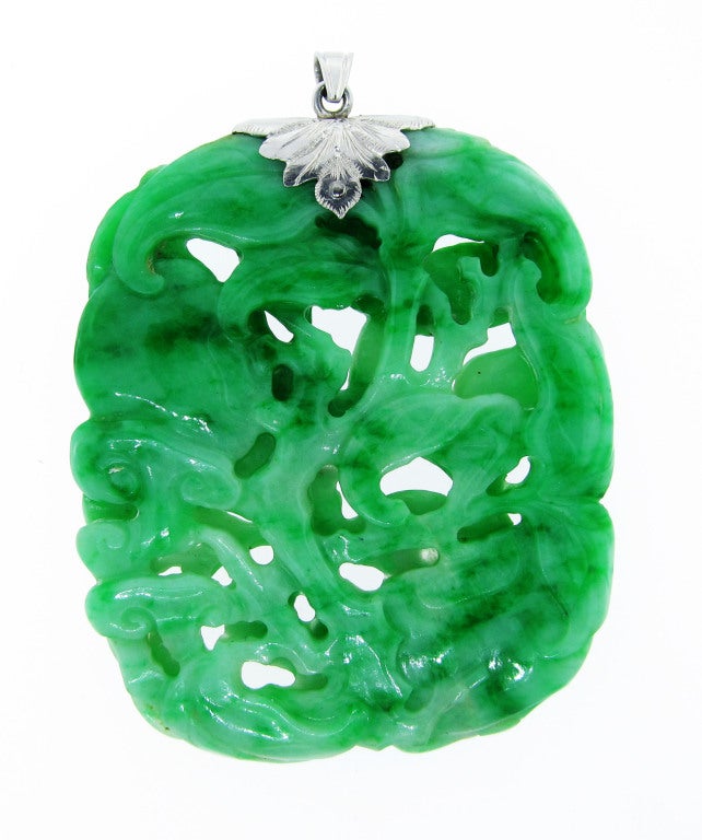 Hand carved and pierced on both sides jade pendant rendered in vine and flower motif. The greens merging from Celadon to rich emerald greens. The platinum bale is bead set with a round old European cut diamond weighing approx..20 cts.