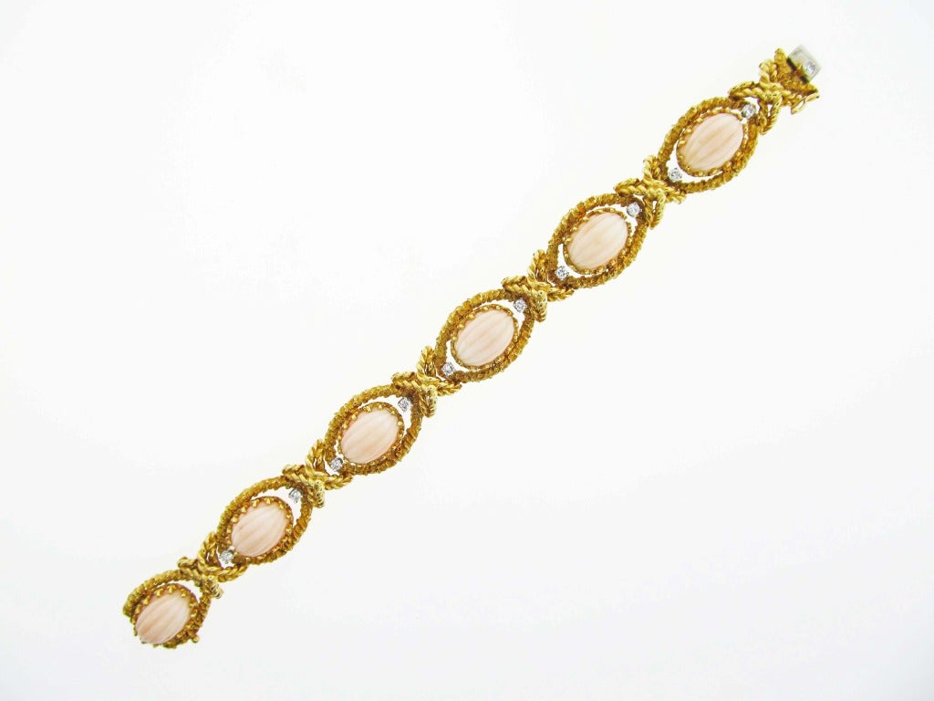 Ropey edge 18kt. yellow gold link bracelet, set with 6 oval natural 13.5mm.x 10mm. corals spaced with 11 round brilliant cut diamonds totaling approx. .50cts. The invisible catch is signed Cellino.