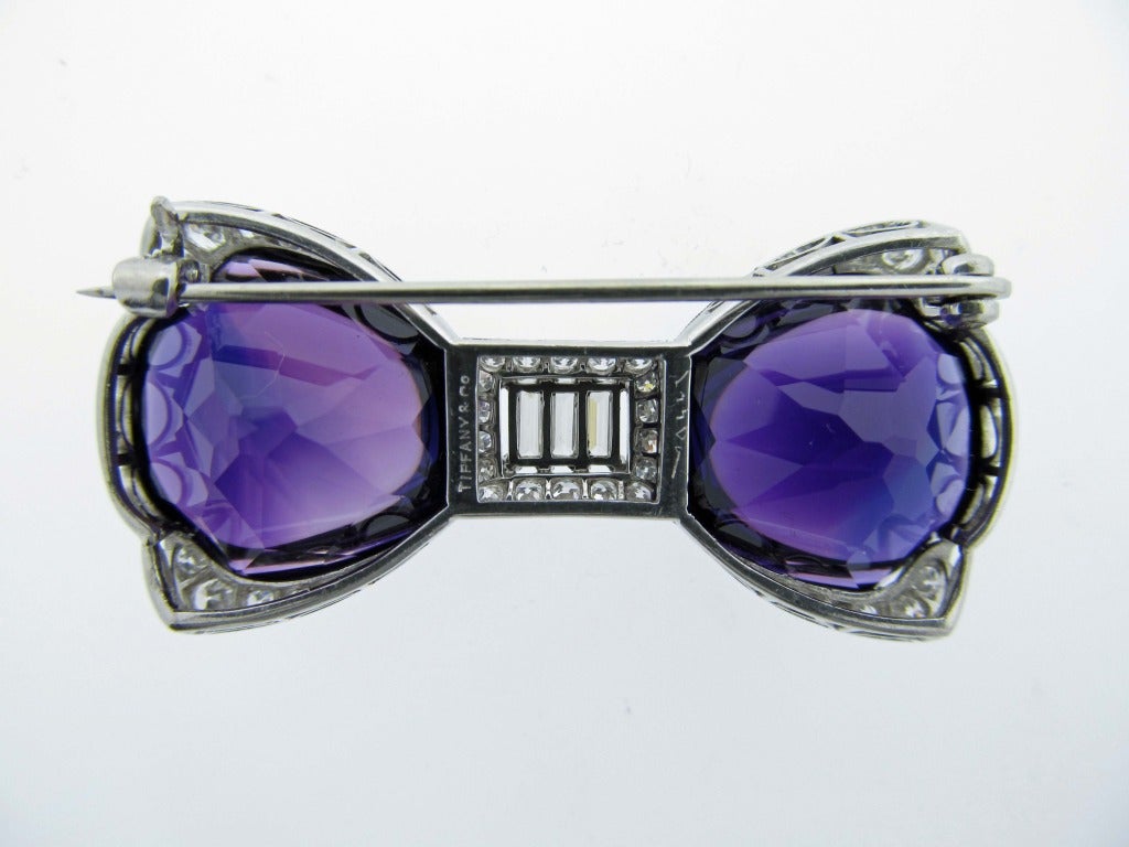 Handmade platinum mount Art Deco bow brooch set with 2 carved top and faceted back rich velvet amethyst. The center is set with three baguette cut diamonds totaling approx..75cts. surrounded by 18 round European  cut diamonds. Each of the four