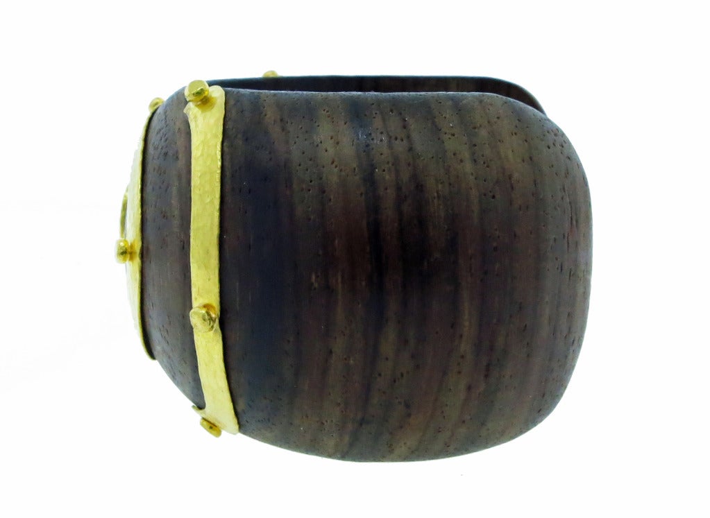 24kt.hammered finish yellow gold inlay wide fruitwood cuff bracelet. The center is bead set with a round brilliant cut diamond weighing approx. .07cts. the bracelet weighs 1 1/2