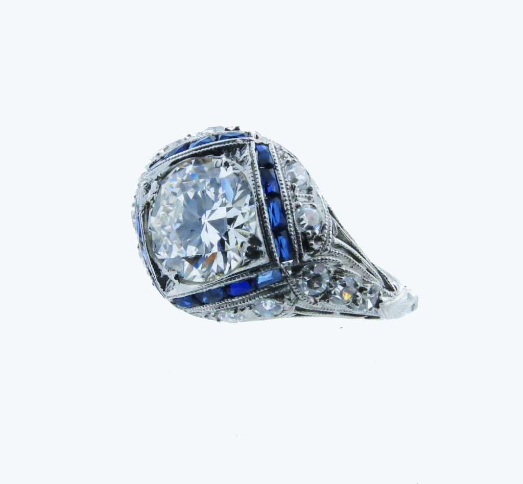 Beautiful platinum mount period Art Deco diamond ring bead set with a round European cut diamond center weighing approx. 1.75cts. grading VS clarity I color surrounded by 15 faceted sapphire baguettes. Also bead set in the open work platinum mount