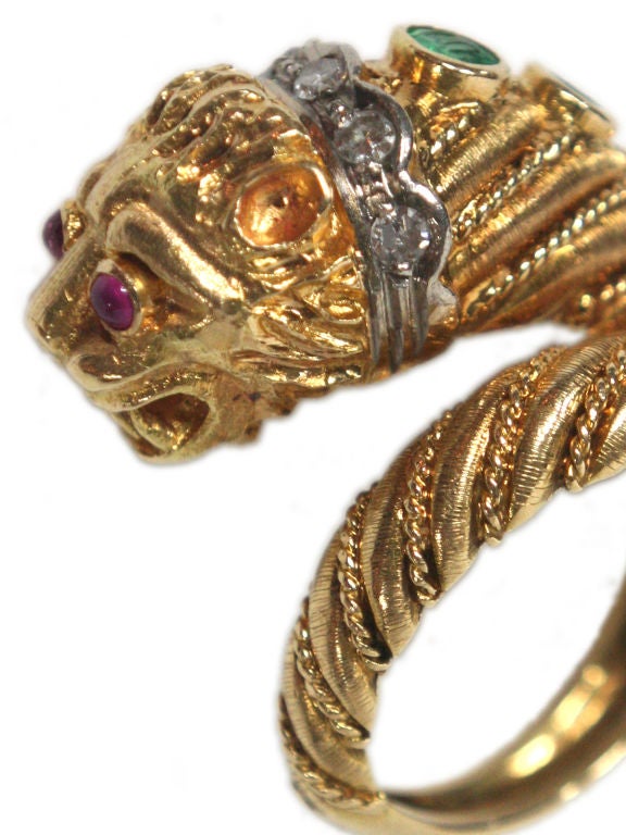 A vintage Lalounis 18 kt gold lion ring with ruby eyes and a diamond collar and emerald spine accents. Size is a 4.5