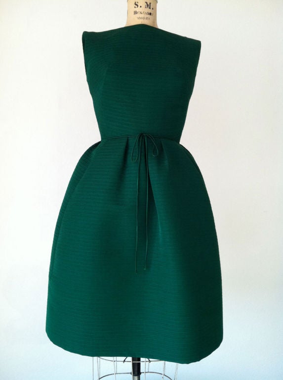 Fine vintage Adele Simpson cocktail dress. Heavy 'emerald' green textured silk fabric item fully silk lined. Item features precision seams, nipped waist, attached belt & zips up back.