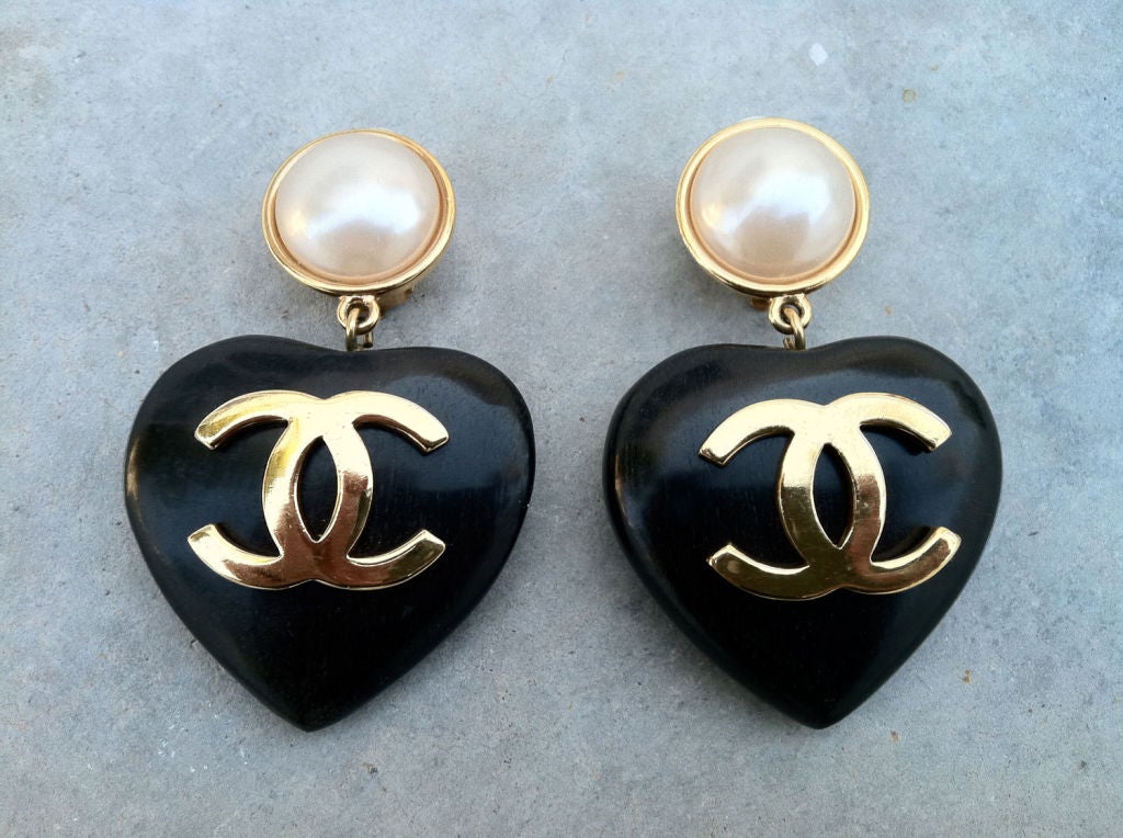 Fine & rare vintage Chanel drop ear clips. Authentic signed gilt metal items with faux 'pearl' centers & original clip backs. Items feature carved wood 'heart' drops with gilt logo centers.