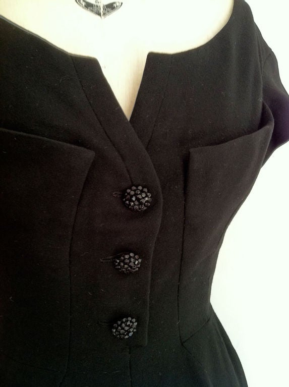 Fine & rare vintage Maggy Rouff afternoon/cocktail dress. Rare & authentic item ca.1950. Fine black wool flannel item fully silk lined with boned bodice. Item features precision seams, layered 'shelf' bust line, faux 'jet' beaded buttons & back