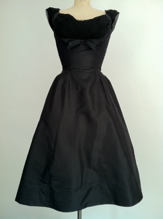 Fine vintage silk & chiffon cocktail dress. Authentic unlabeled item from the 1950s actress/model Joan Kemp estate. Black silk matte satin item features a ruched chiffon 'shelf' bustline & matching back draping. Item fully lined with a nipped waist,