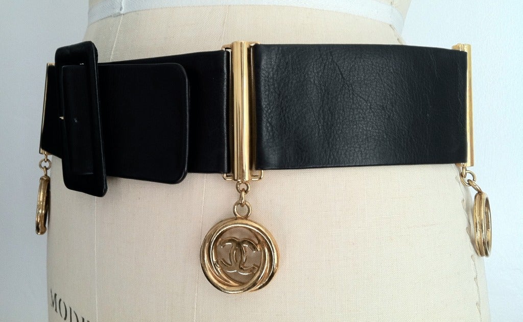 Fine and rare vintage Chanel cinch belt with attached 'charms'. Fine black leather item features gilt metal spacers and attached hanging logo charms.