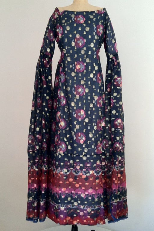 A rare vintage Tina Leser lantern sleeved gown. Authentic synthetic organza print item with gold metallic details. Item fully lined, zips up back with off center front vent. Floor length vented sleeves open at 3/4 length.