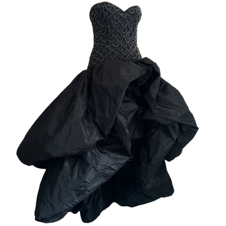 A exquisite and rare vintage Loris Azzaro Couture ball gown. Couture client numbered item (#113) constructed of a fine black silk and cut above the knee. Item features a precisely crystal beaded boned bodice with attached interior waist belt.