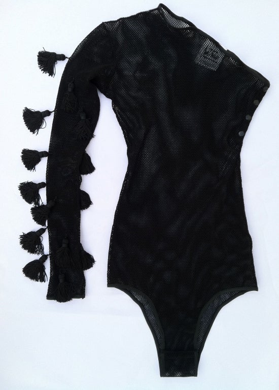 A fine and rare vintage Angelo Tarlazzi mesh bodysuit. Black stretch mesh single arm item trimmed with silk tassels.