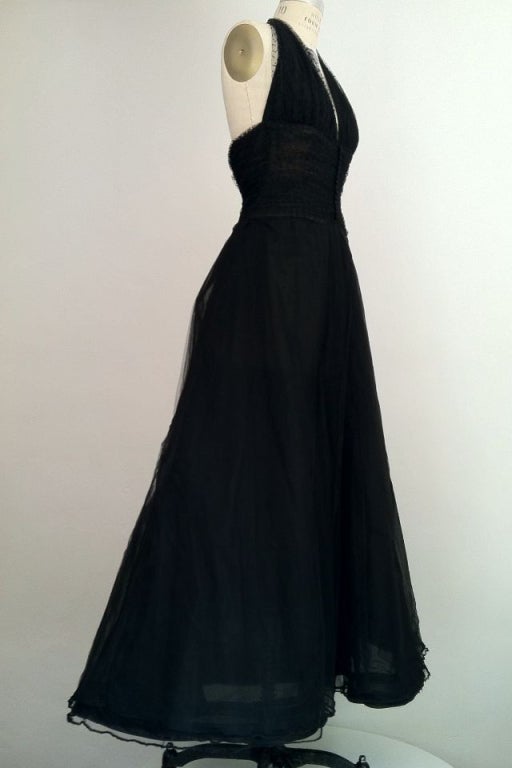An exquisite vintage Oscar de La Renta ball gown. Layers of black tulle cover a horsehair stiffened floor length underskirt. Gown features a dotted tulle halter boned bodice. Item fully lined and zips up back. Stunning!