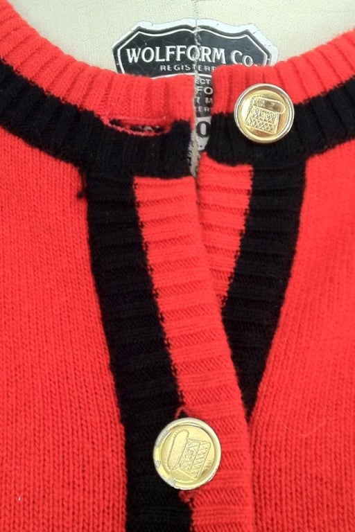 A fine vintage and iconic Chanel cashmere cardigan sweater. Vibrant red knit item trimmed in black with gilt metal Chanel buttons.