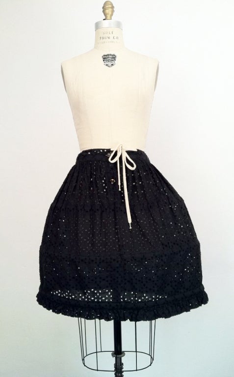 A fine vintage and iconic Vivienne Westwood mini-crini hoop skirt. Black eyelet fabric item features a drawstring and button waist closure and 3 plastic hoops.
