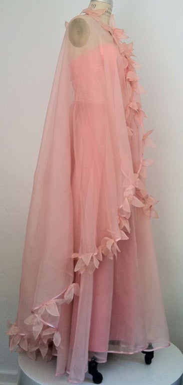 A fine and rare vintage Loris Azzaro Haute Couture evening dress and cape ensemble. Pale pink sheer silk organza full cape trimmed with sculpted flowers with faux 'pearl' centers. Cape features a single hook closure at neck. Matching strapless gown