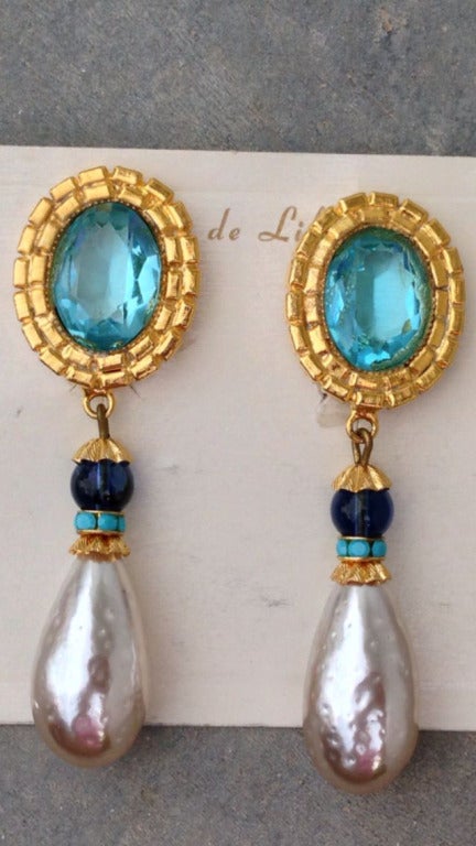 A fine vintage pair William de Lillo ear drops. Signed gilt metal items feature faux aquamarine centers and large 'Baroque' pearl drops. Original clip backs and hang tag intact.

Rare item from the William de Lillo archives.

William de Lillo