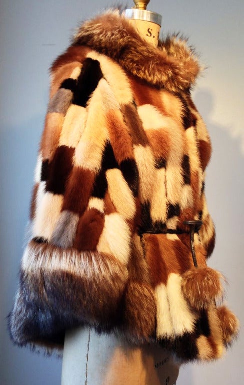 A fine vintage Bonwit Teller mink patchwork poncho. Authentic mink fur Bonwit Teller item trimmed in raccoon fur. Item fully silk lined with a brown leather cord half-hidden self tie belt. Belt trimmed in matching raccoon fur 'puffs'. Item features