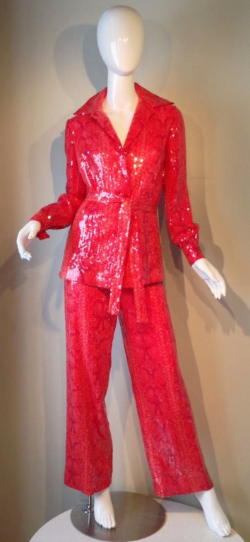 A fine vintage Bill Blass sequin trouser suit. Clear sequins cover a snakeskin printed stretch jersey. Jacket features hidden snap closures plus original matching sash belt. Trousers feature a elastic waistband.