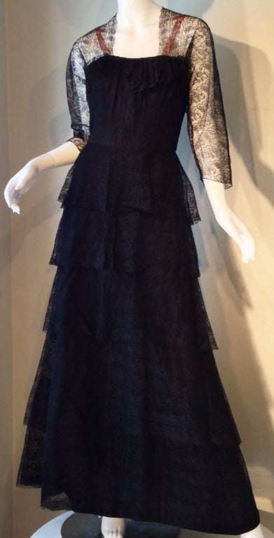A fine and rare vintage Adrian lace gown. Gorgeous and delicate tiered black lace item features a boned bodice. Item buttons and zips up back. A rare and important item appropriate for any collection or archive.