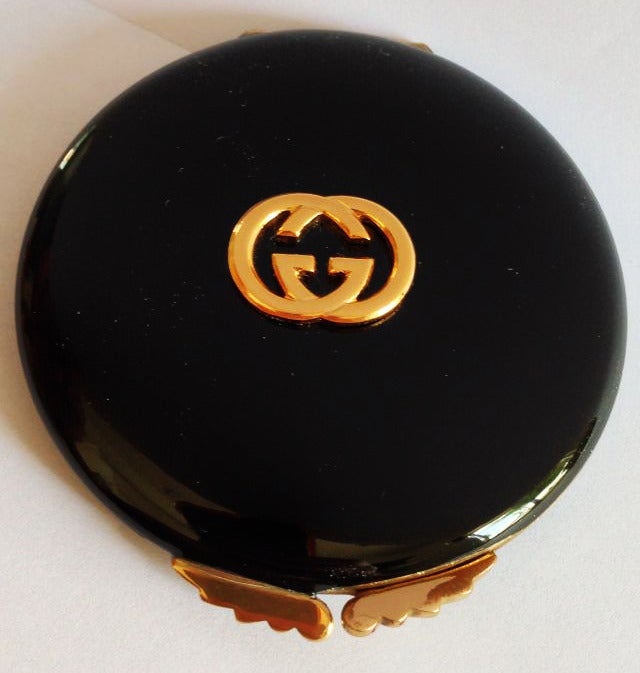 A fine and rare vintage Gucci compact. Black enamel and gilt metal item conceals two round vanity mirrors.