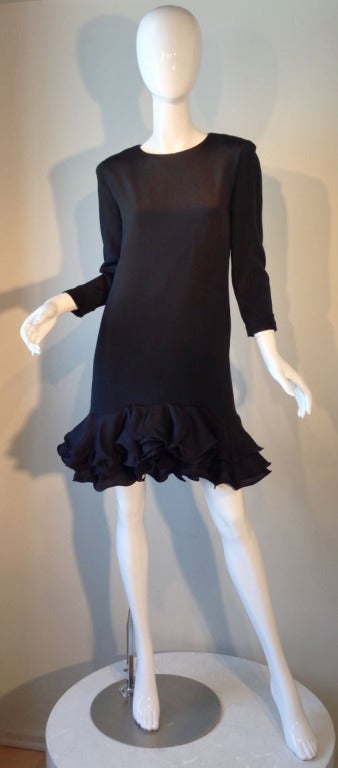 A fine vintage Pierre Cardin cocktail dress. Black silk item features a sculpted layered hemline and banded sleeve trim. Item fully lined and zips up back.