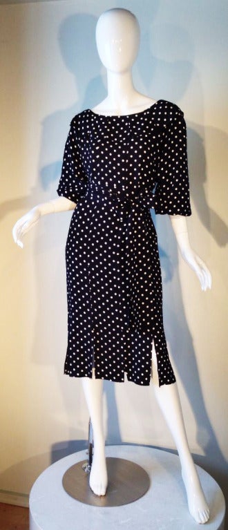 A fine and rare vintage Yves Saint Laurent afternoon/cocktail dress. Dotted black crepe item features a 'car wash' hem line and collar. Item slips over head (no zipper) and matching fabric sash belt.