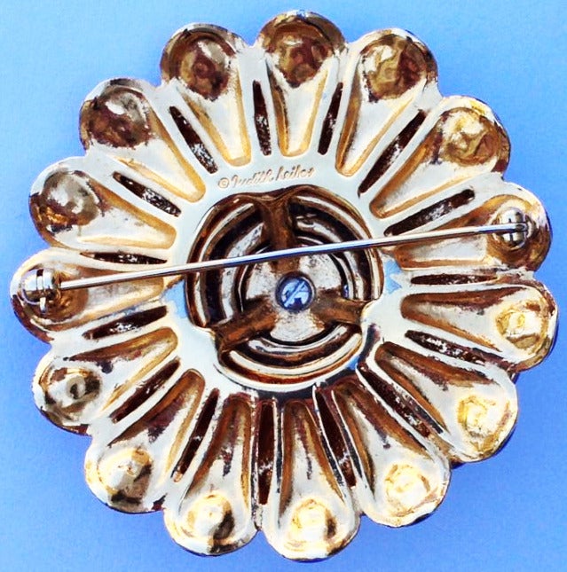 A fine and rare vintage Judith Leiber floral theme brooch. Signed gilt metal item features enamel 'petals' and a pave set crystal center.