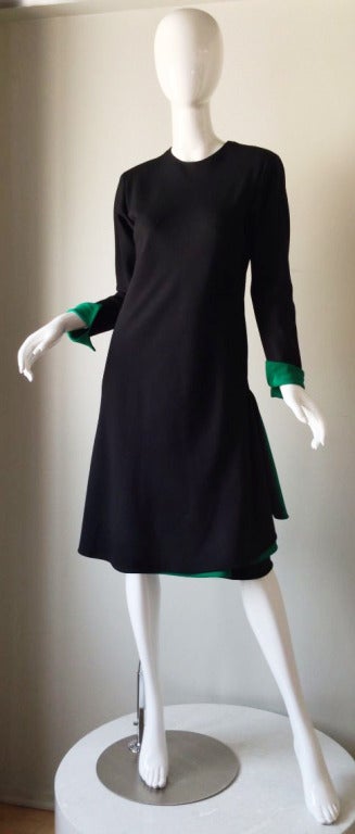 A fine and rare Halston afternoon/cocktail dress. Fine black spiral seam/bias cut black silk item features a contrasting emerald green lined cuffs and skirt trim. Item fully silk lined with a spiral set hidden zipper up back. A understated yet chic