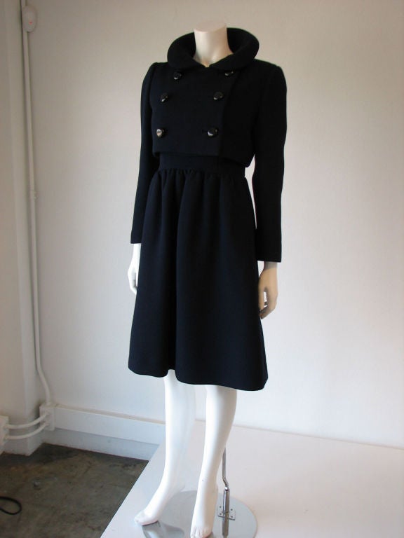 Fine vintage Norman Norell navy blue 2pc. dress & jacket suit. Sleeveless fitted waist dress fully lined & zips up side with hooking shoulder closures. Item features full skirt with hidden side pockets & matching fabric cropped double breasted