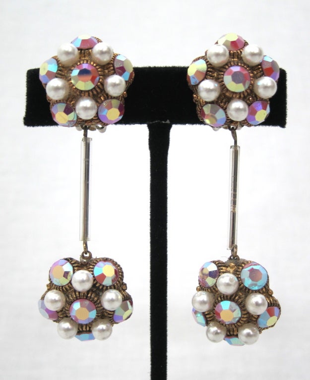 Featured is a lovely pair of vintage earrings from the 1960s. Faceted iridescent pink crystals and faux pearls in a gold tone setting. Strong clips.

Length: 3