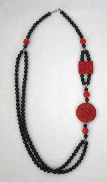 Featured is a fabulous vintage necklace from the 1960s-70s. Assymetrical double strand of black beads with accents of carved faux cinnabar beads. Strong fishhook clasp.

Length: 37