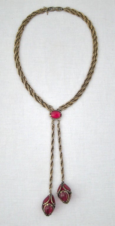 Featured is a gorgeous vintage saucier necklace by Trifari, circa the late 1950s-1960s. Double strand gold tone twisted chain accented with twin pendants and Raspberry glass cabochons. Strong fold over clasp and metal hang tag. 

Length: