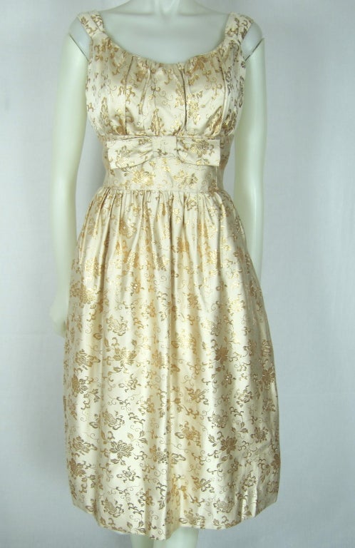 Gorgeous Gold metallic floral cream silk  shelf bust with bow party dress. Has a side metal zipper. Excellent condition..Rare!  Flattering!

Bust 36