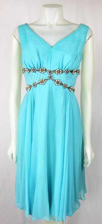 This is a beautiful 1970s aqua colored chiffon dress with pearls rhinestones bugLE beads and studded rhinestones  It has a full skirt, so the dress will flow when you walk in it. It has a v-neckline and is sleeveless.  Fully lined. 
BUST :