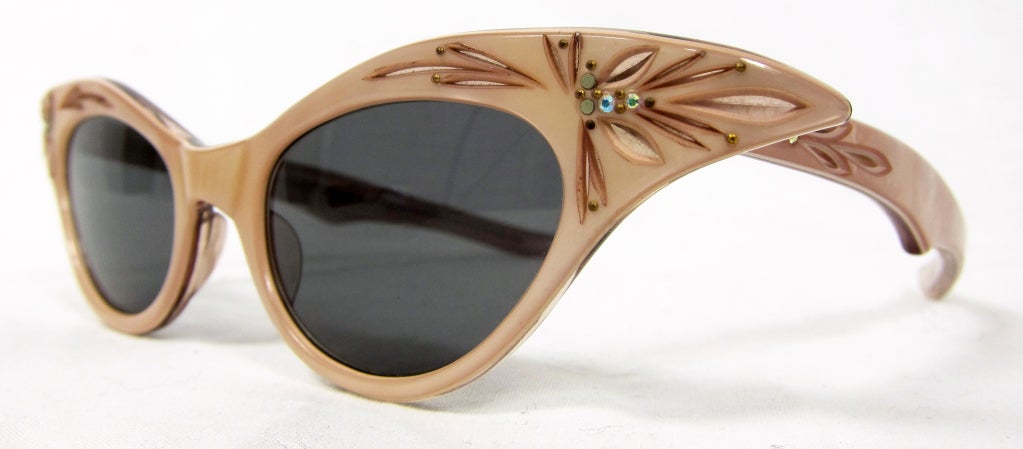 Vintage cat eye sunglasses with rhinestone and engraving details next to lenses and on temple arms. The color has more of a beige rose pearlized look not as brown as shown in pictures .

Size - 46 - 20
Front Width - 6 3/4