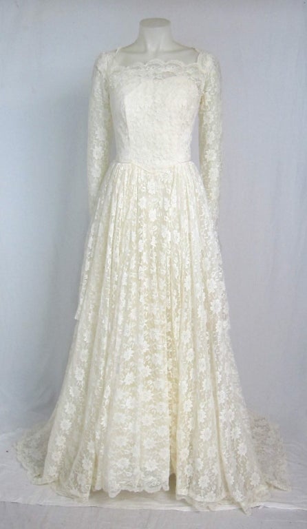 This is a beautiful ivory lace wedding dress with long sleeves that end in a point with snap closures.  it has sweeping train that graces the floor. There are  iridescent sequins along the scalloped hem lines.  A sweetheart neckline with scalloped