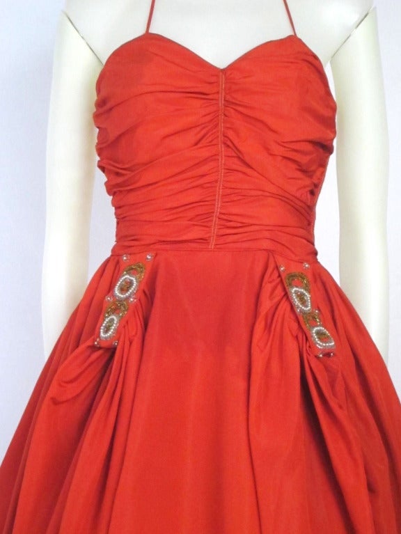 This is a beautiful Fred Pearlberg red halter taffeta party dress! 
The  halter bodice is ruche (flattering) with boning and a  full skirt with gathered fabric and embellished beaded appliques providing additional interest to the swoosh of the
