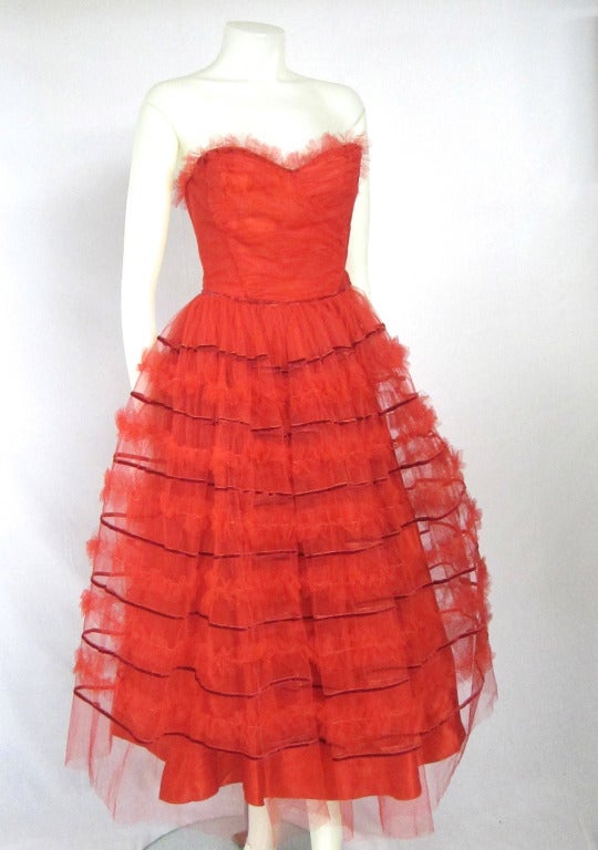 This is a gorgeous  strapless bright red full tulle with bands of red velvet  party or wedding dress!  .  Bust has boning , a comfort strap and side metal zipper. Very Exciting! 
Bust: 32