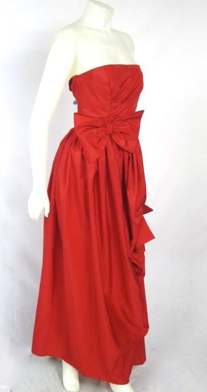 This is a beautiful red taffeta strapless ball gown or wedding dress. It has a big bow at the waist and draped at the side with another lovely bow.  Has boning at the sides  Gorgeous! 

Bust: 34