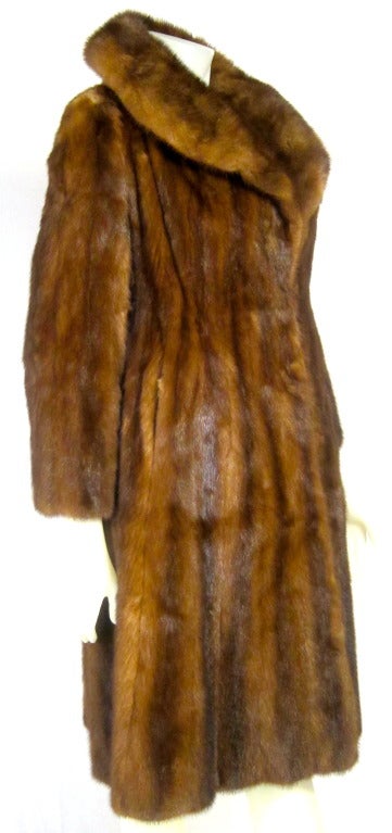 This is a late 1950's Dark Caramel Full Length Princess Cut Mink coat It is soft and supple and the lining is with embroidered Roses. There is a waist strap, pockets and hook eye closure. My former father -in- law was a furrier in Hollywood. 
Bust: