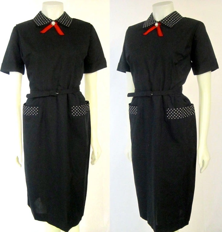 Wonderful 1950s cotton black dress . Black and white polka dot pocket trim and collar with red  bow faux pearl decorative button.  The dress has matching belt and metal zipper. Appears to not have been worn.
One belt loop missing, minor wear on